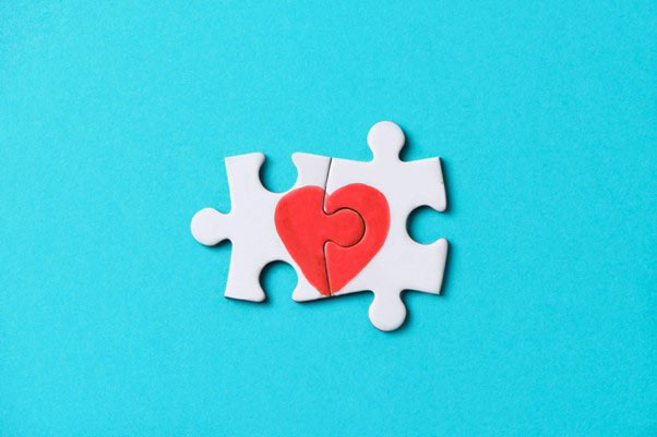 Two puzzle pieces connect to form a heart design.